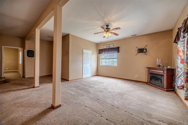 unfurnished living room with ceiling fan, baseboards, a glass covered fireplace, and carpet