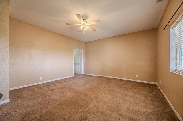 unfurnished room featuring light carpet, a ceiling fan, baseboards, and a wealth of natural light