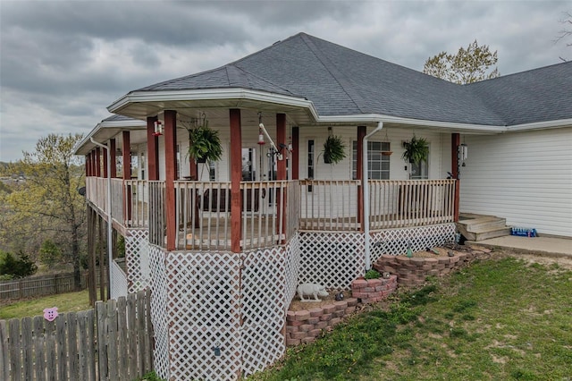 exterior space with fence, a shingled roof, and covered porch