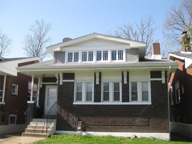 bungalow featuring brick siding and a chimney