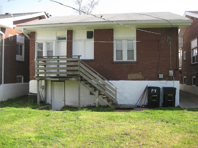 rear view of house with brick siding, stairway, a shingled roof, and a lawn