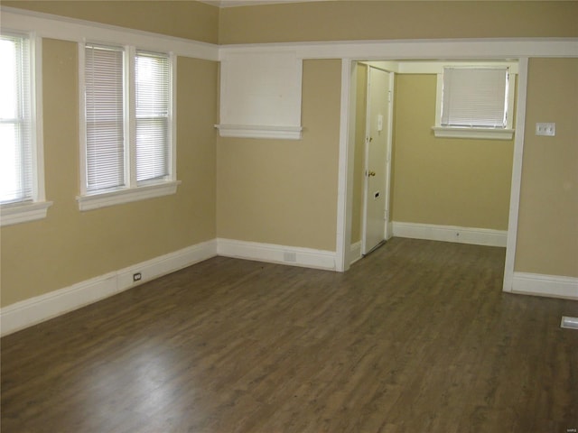 spare room with baseboards and dark wood finished floors