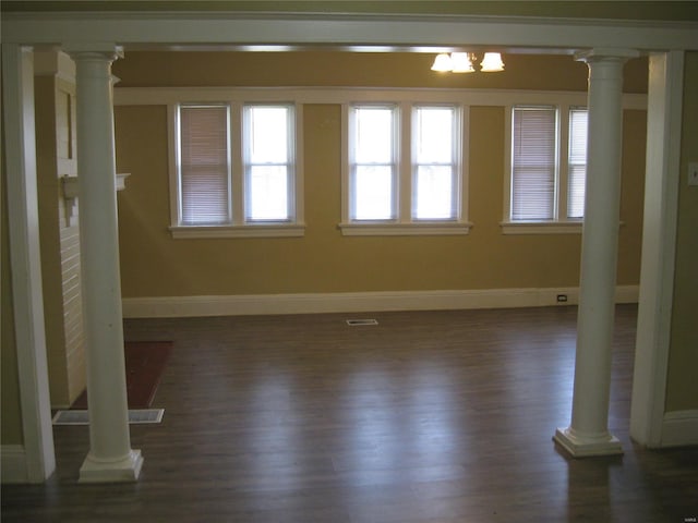 interior space featuring dark wood-type flooring, ornate columns, baseboards, and visible vents