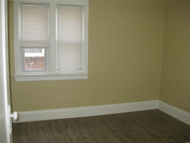 spare room featuring dark wood-style flooring and baseboards