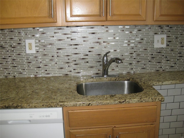 kitchen featuring a sink, backsplash, light stone counters, and dishwasher