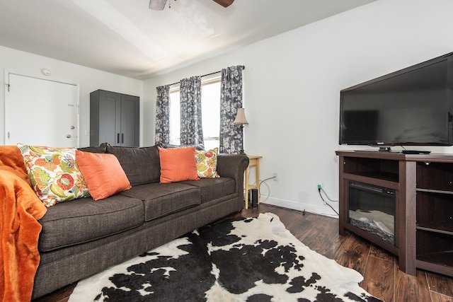 living room featuring baseboards, ceiling fan, and dark wood-type flooring