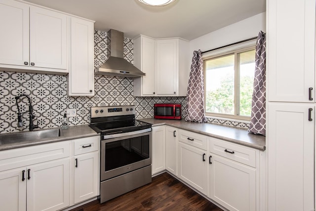 kitchen with wall chimney range hood, backsplash, stainless steel electric range, and a sink