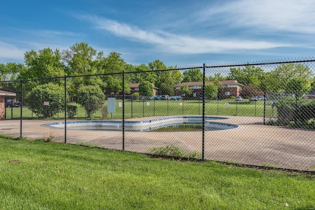 view of tennis court with a lawn and fence