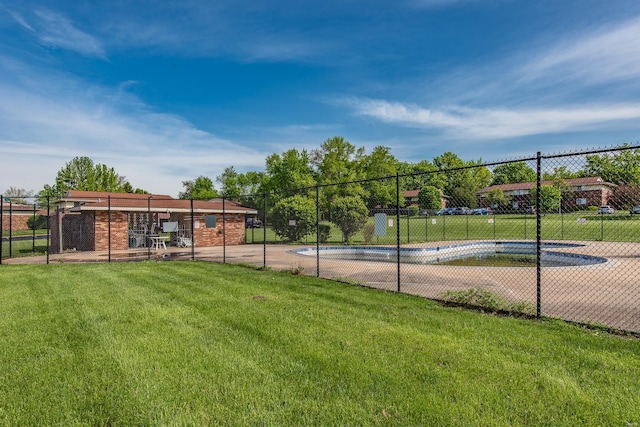 view of tennis court with fence, a community pool, and a yard