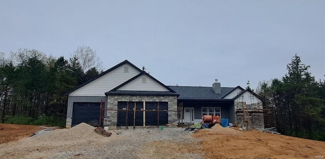 view of front facade with a chimney, stone siding, and a garage