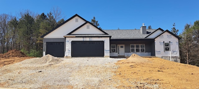 view of front facade featuring a garage, driveway, covered porch, and a chimney