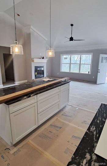 kitchen featuring a ceiling fan, open floor plan, a glass covered fireplace, and white cabinetry