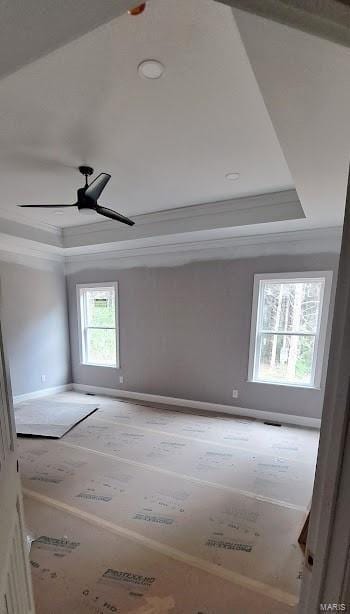 unfurnished room featuring a ceiling fan, a tray ceiling, ornamental molding, and baseboards