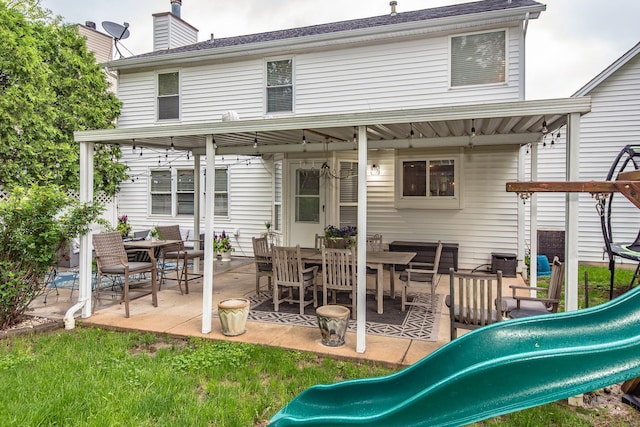 rear view of house with a playground, a patio area, and a chimney