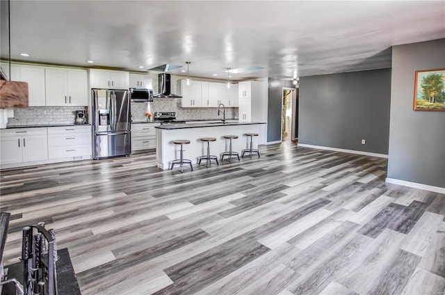 kitchen featuring tasteful backsplash, a sink, wall chimney range hood, dark countertops, and stainless steel appliances