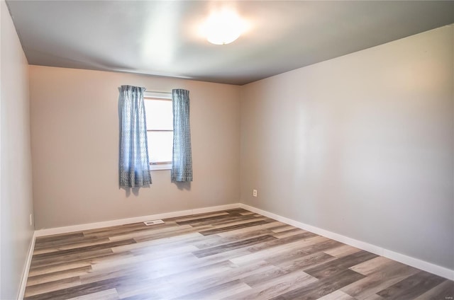spare room featuring visible vents, baseboards, and wood finished floors