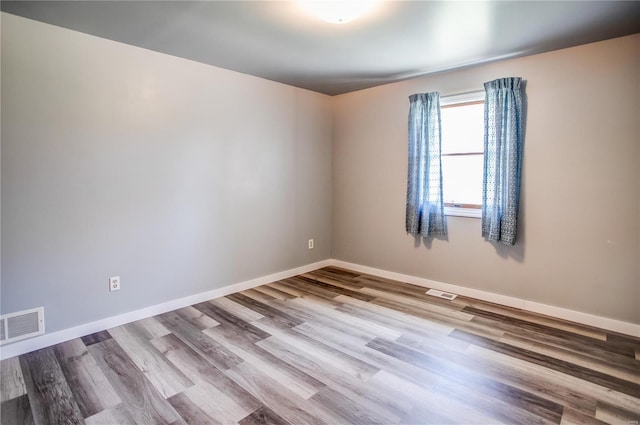 empty room with visible vents, baseboards, and wood finished floors
