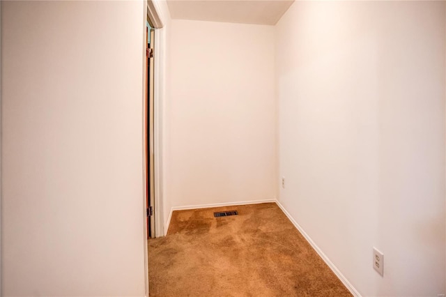 hallway featuring baseboards, visible vents, and carpet floors