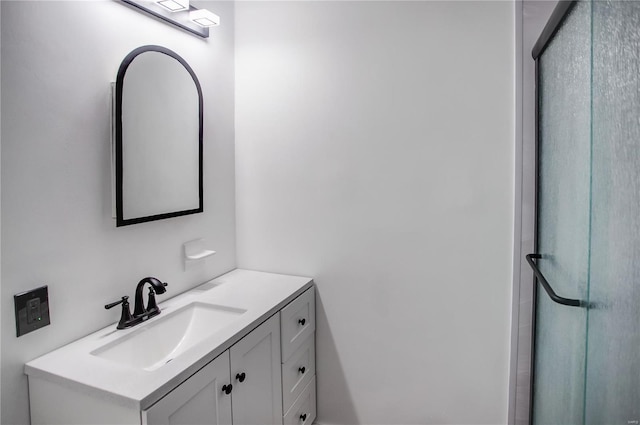 full bathroom featuring a shower with shower door and vanity