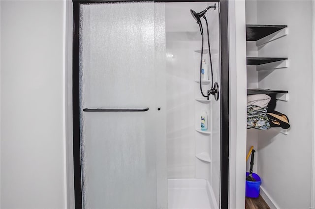 full bathroom featuring a stall shower, wood finished floors, and baseboards