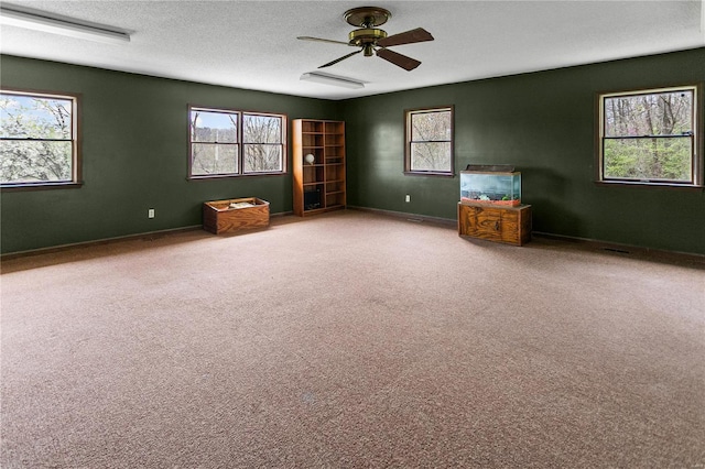 unfurnished room with carpet floors, baseboards, a ceiling fan, and a textured ceiling