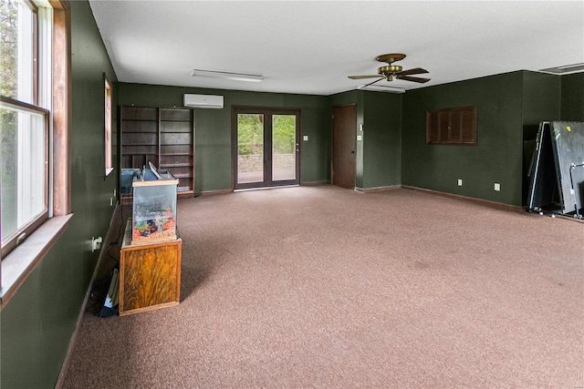 unfurnished living room featuring a ceiling fan, baseboards, an AC wall unit, and carpet floors