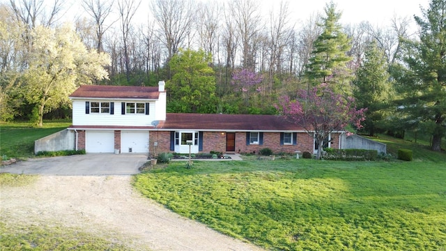 view of front of home with a chimney, driveway, a front yard, brick siding, and a garage