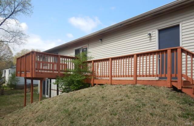rear view of house featuring a wooden deck and a yard
