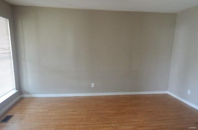 unfurnished room featuring baseboards, light wood finished floors, and visible vents
