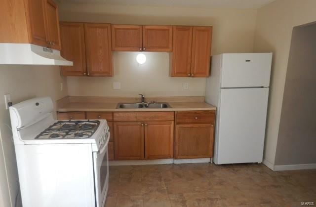 kitchen with a sink, range hood, white appliances, and light countertops