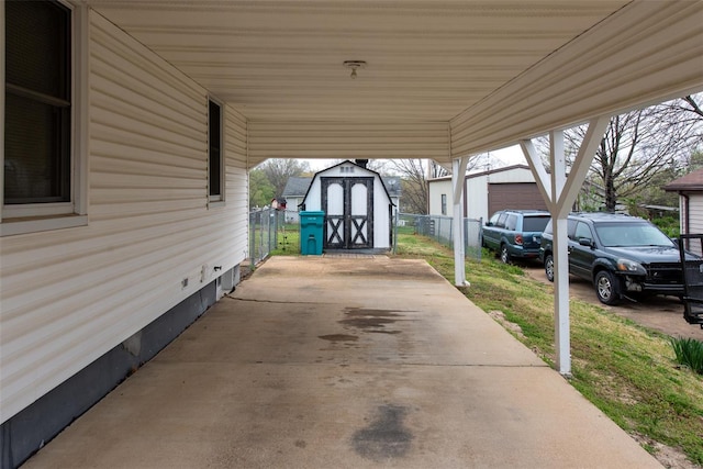 view of patio featuring a carport, fence, an outdoor structure, and a storage unit