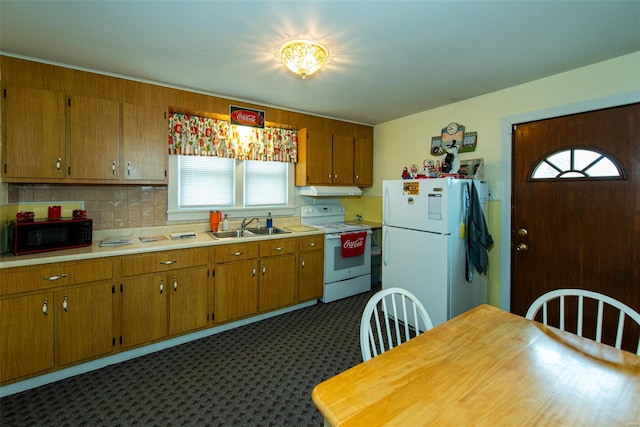 kitchen featuring brown cabinetry, a sink, light countertops, and white appliances