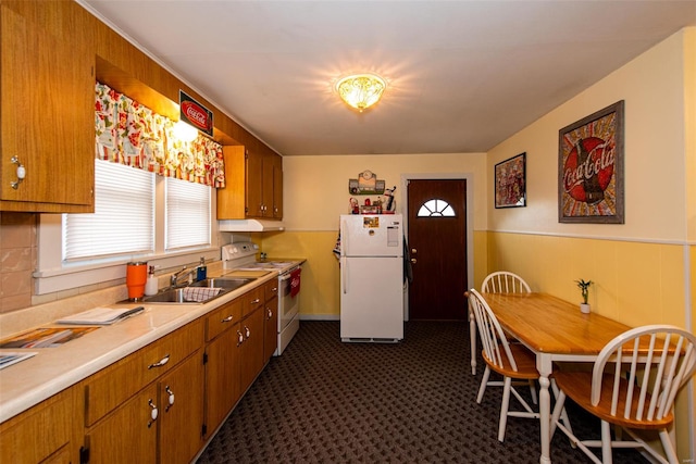 kitchen with a sink, light countertops, white appliances, under cabinet range hood, and brown cabinetry