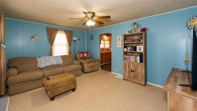 living room featuring arched walkways, carpet flooring, ceiling fan, and baseboards