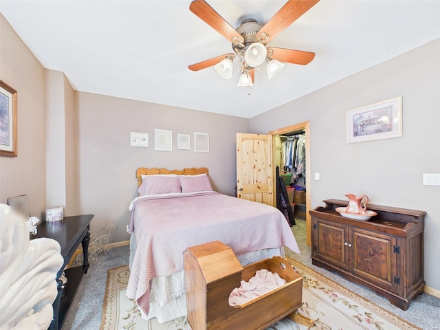 bedroom featuring a closet, baseboards, a ceiling fan, a walk in closet, and light carpet