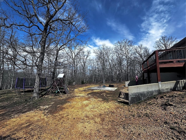 view of yard featuring a trampoline and a wooden deck