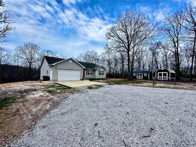view of front of house featuring an attached garage, an outdoor structure, and gravel driveway