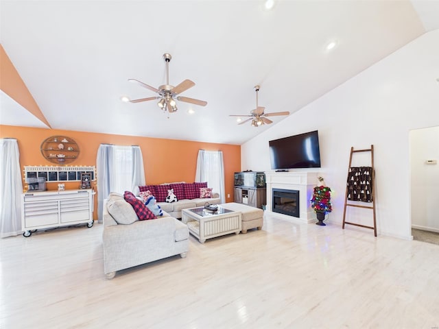 living area with a glass covered fireplace, recessed lighting, light wood-style flooring, a ceiling fan, and high vaulted ceiling