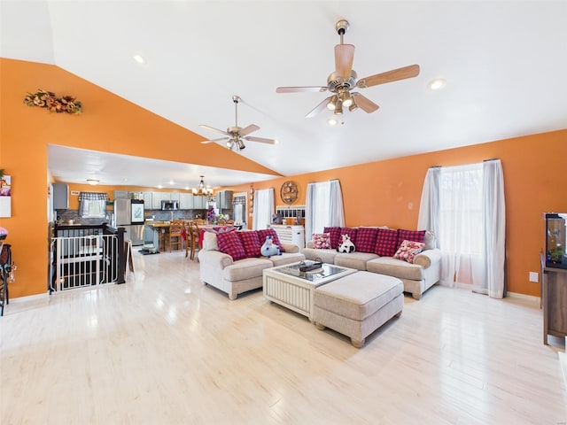 living room with high vaulted ceiling, light wood-style floors, and ceiling fan with notable chandelier