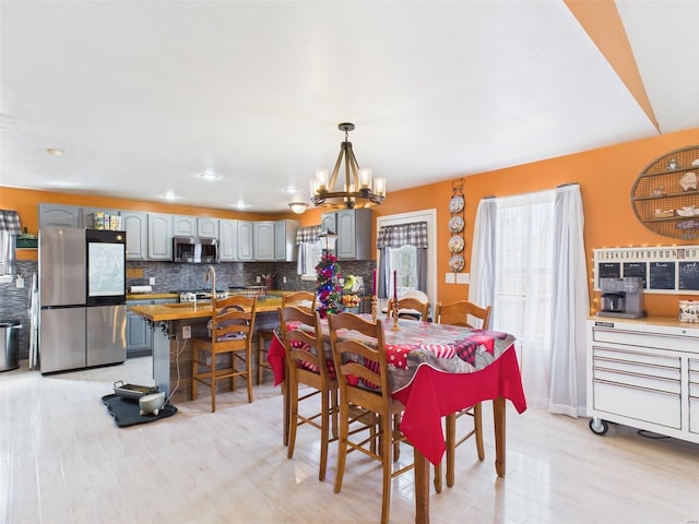 dining space with light wood finished floors and an inviting chandelier