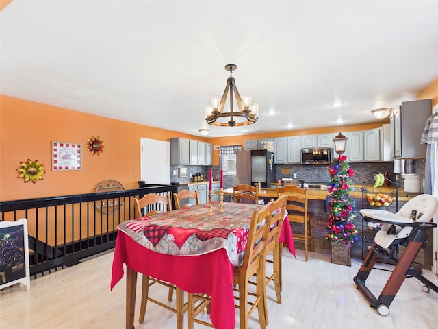 dining space with light wood-style floors and a notable chandelier