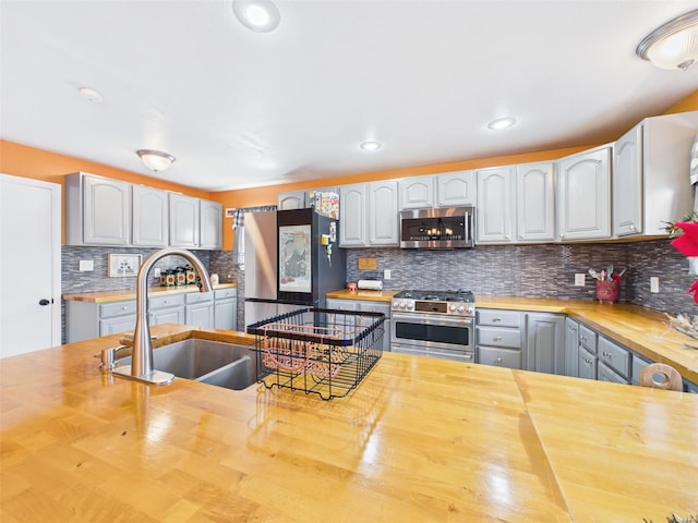 kitchen featuring a sink, recessed lighting, stainless steel appliances, butcher block countertops, and backsplash