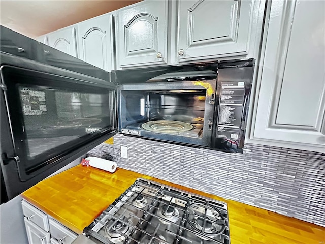 interior space with butcher block counters, backsplash, wood finished floors, and white cabinetry