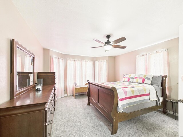 bedroom featuring light colored carpet, baseboards, and a ceiling fan