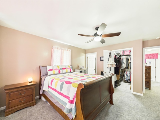 bedroom featuring light carpet, a closet, baseboards, and a spacious closet