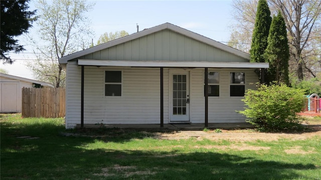 rear view of property featuring fence and a lawn
