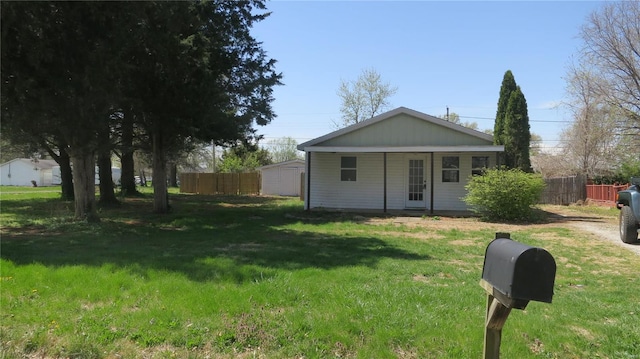 view of front of property with an outbuilding, fence, and a front lawn