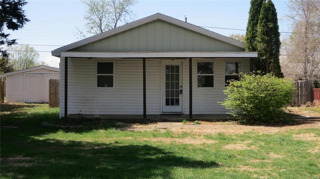 rear view of house with an outbuilding, fence, a lawn, and a storage unit