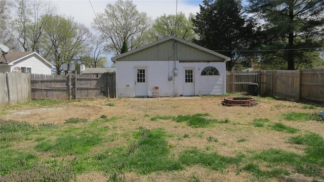 view of outdoor structure featuring a fenced backyard and an outdoor fire pit