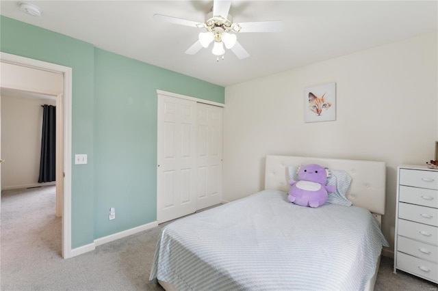 bedroom with a closet, baseboards, a ceiling fan, and carpet